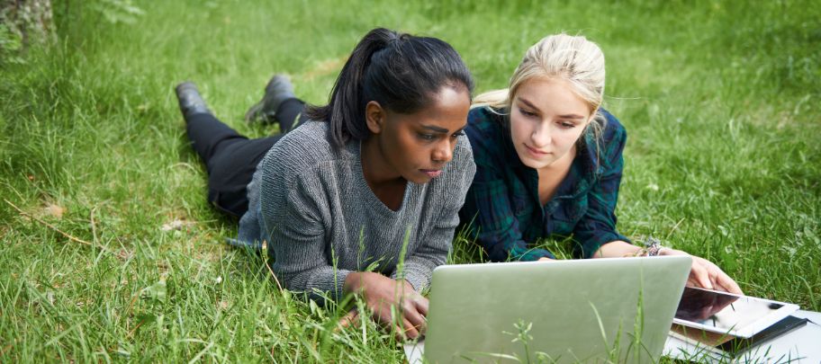 Two girls looking at computer in a field